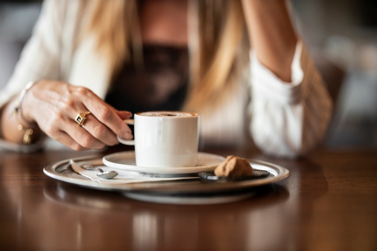 Una donna prende un caffè seduta a un tavolo 