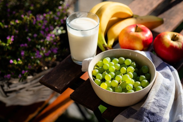 Un bicchiere di latte vegetale e frutta su un tavolino accanto all'albero di Natale