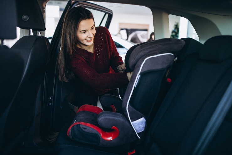 Una donna sistema il seggiolino auto sui sedili posteriori