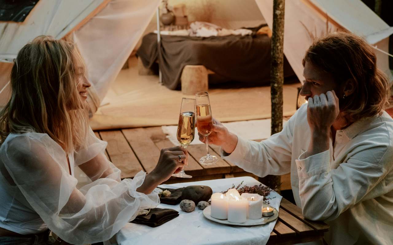 Una coppia fa un brindisi durante una fuga romantica in un glamping