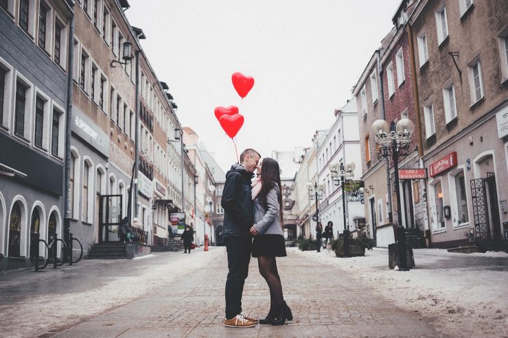 Una coppia in mezzo alla strada con dei palloncini a forma di cuore